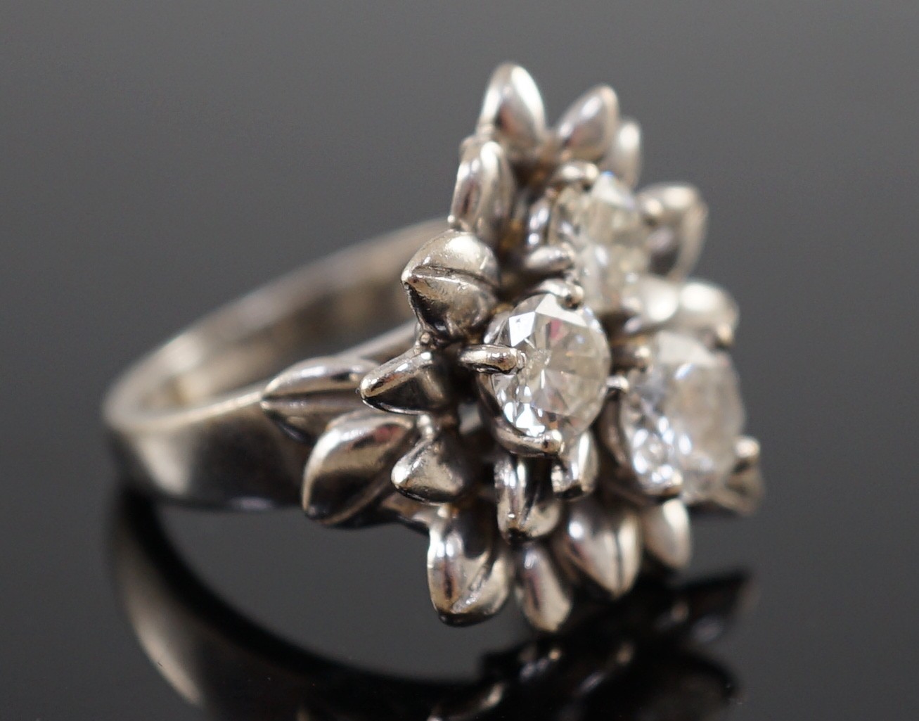 An 18ct white gold and three stone diamond set flowerhead ring